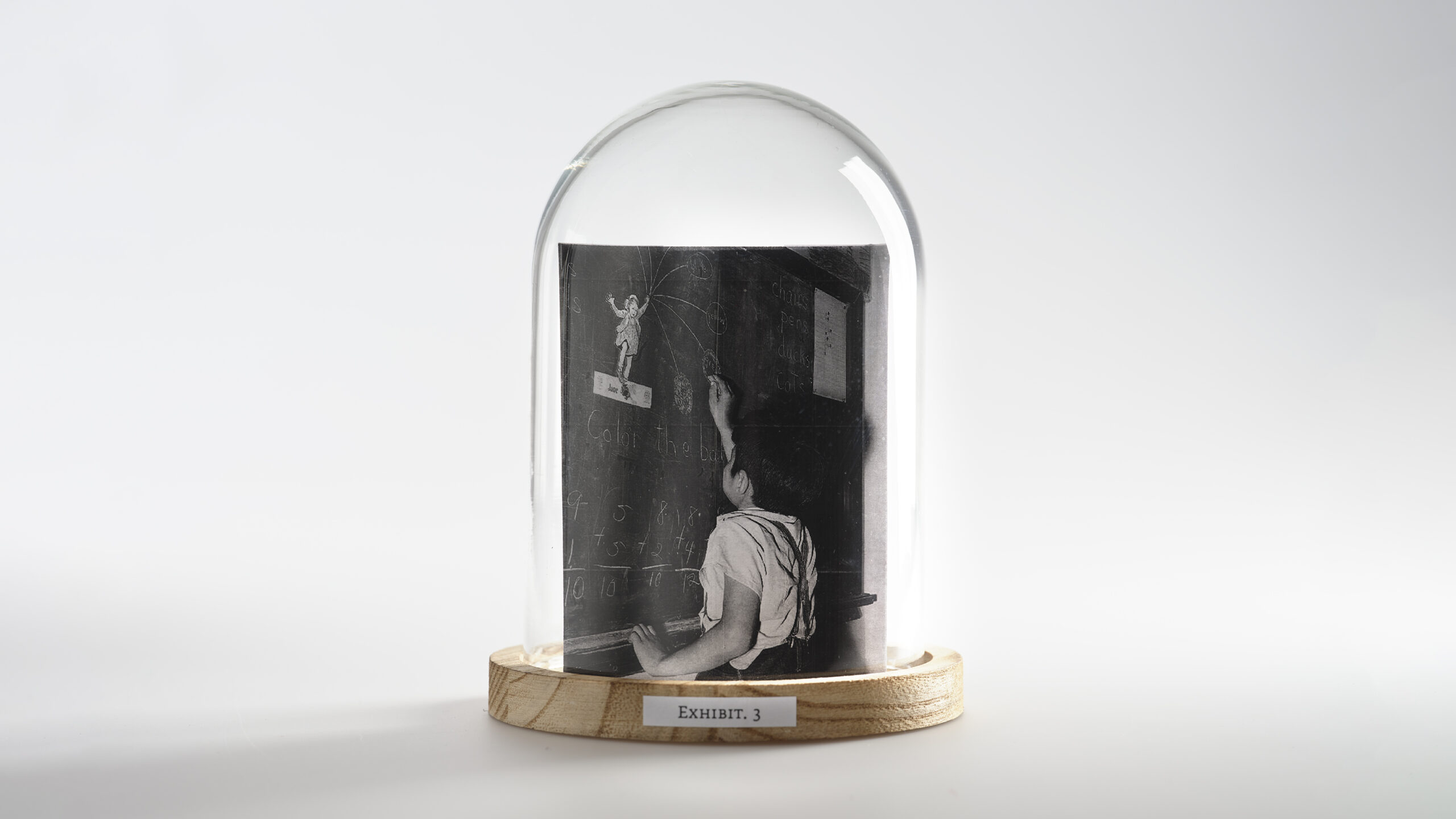 A bell jar with an image of a child writing on a chalkboard inside.