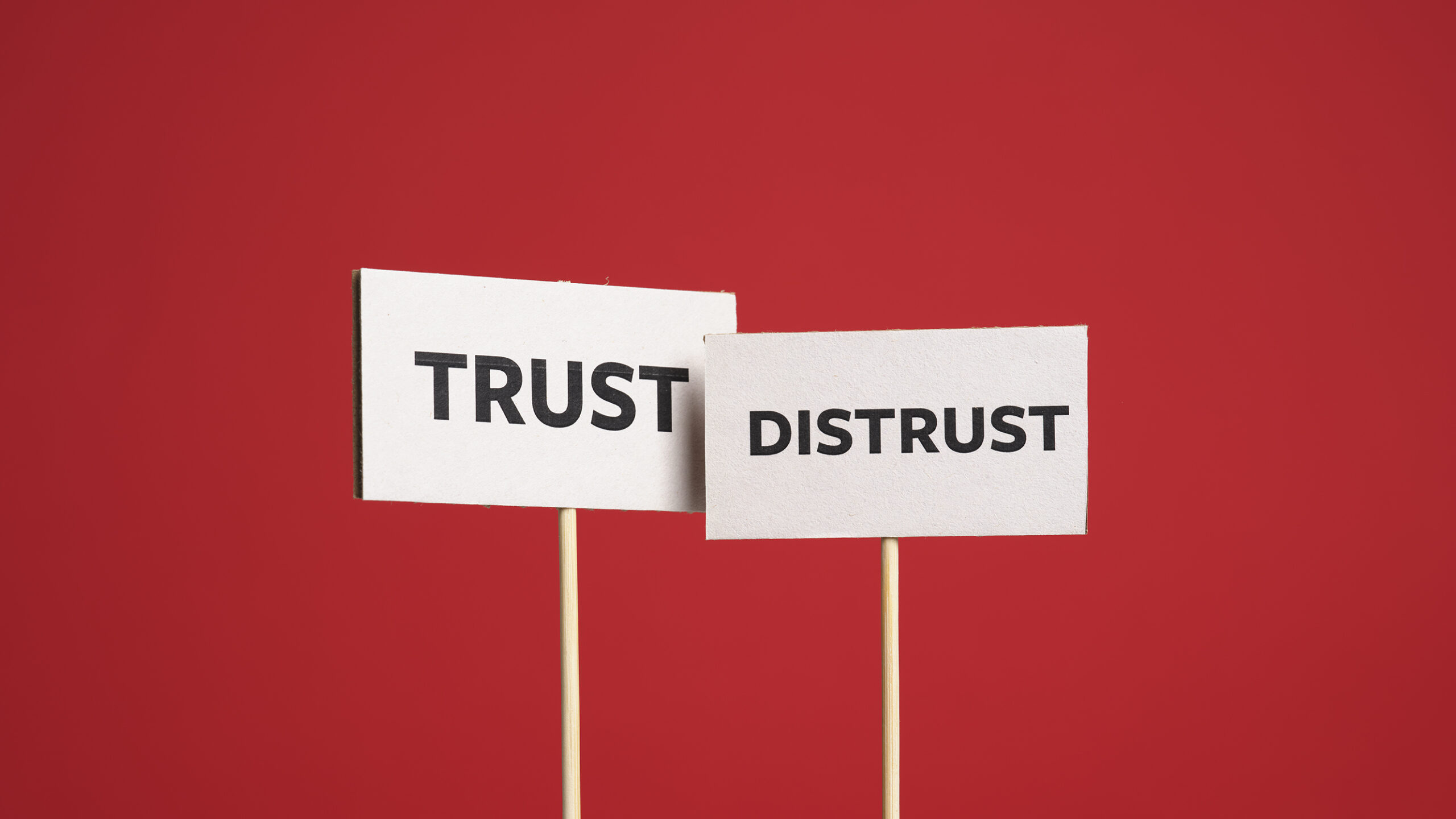 Two placards reading "Trust" and "Distrust", against a red background.